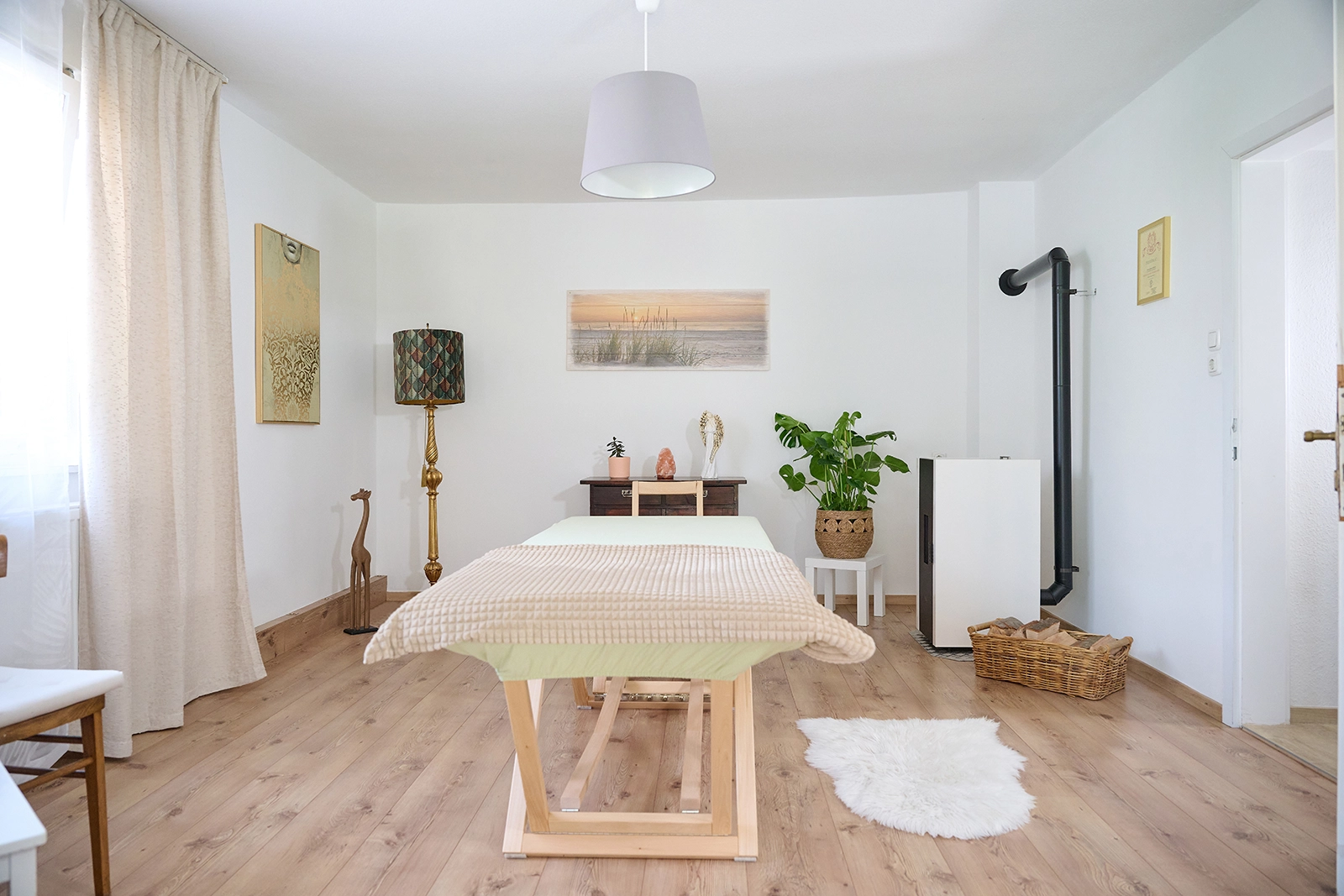 Heller Praxisraum mit Behandlungsliege, Pflanzen und ruhiger Atmosphäre.